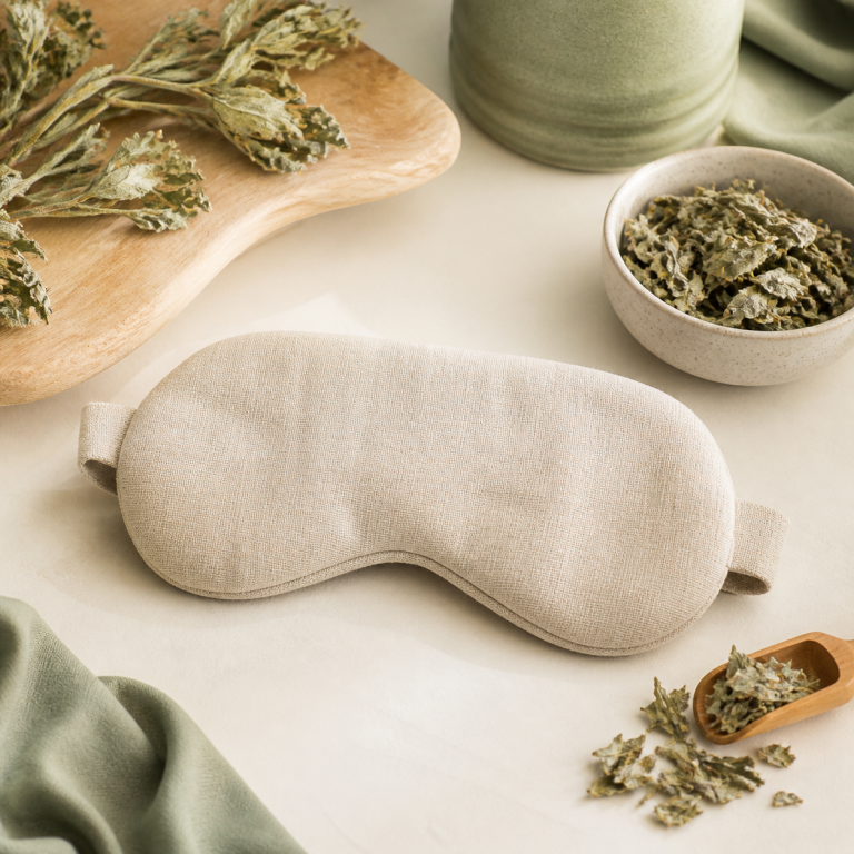 Unbranded herbal eye mask arranged with mugwort leaves and natural fabric